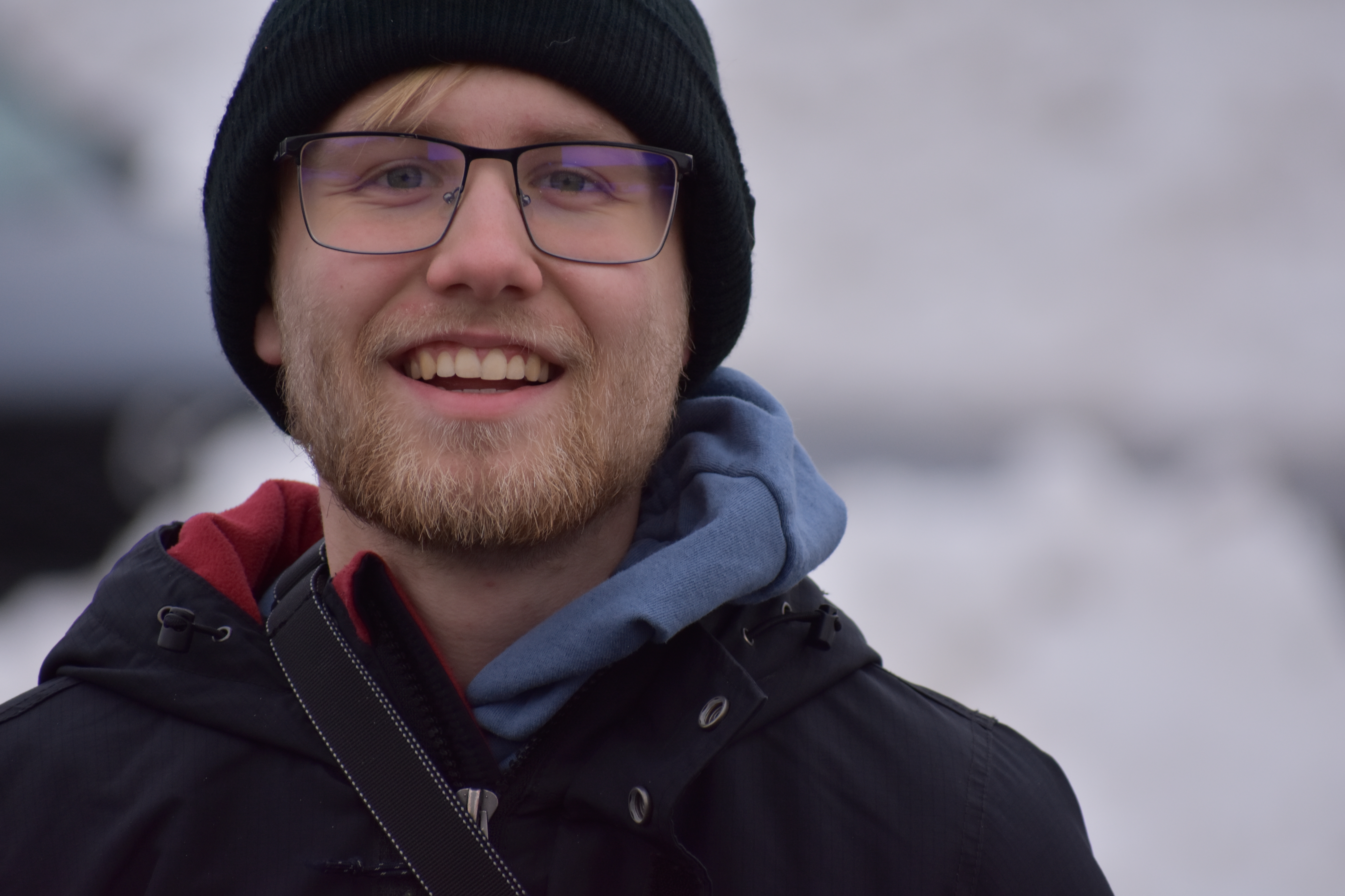 Portrait of Carson Motowski wearing glasses and a blue sweater
